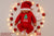 Baby in red Christmas outfit surrounded by festive decorations on a light background